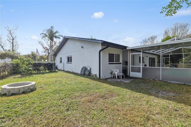 back of property with a yard, a fire pit, and a lanai