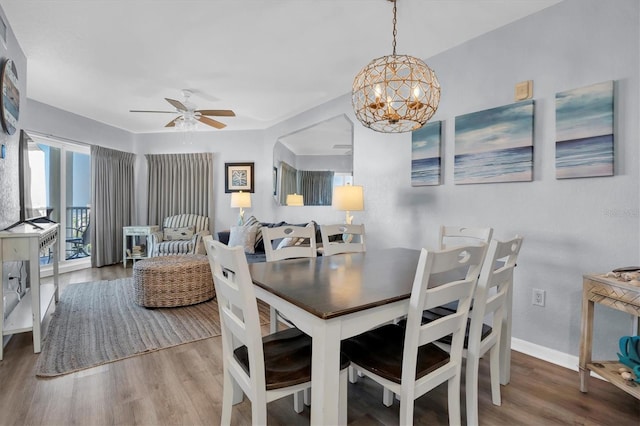 dining room with wood-type flooring and ceiling fan with notable chandelier