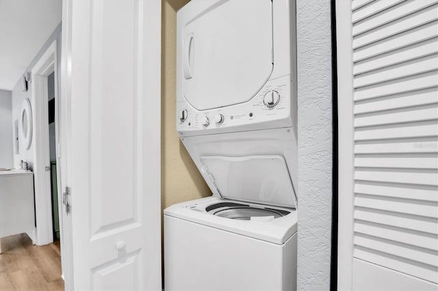 clothes washing area featuring stacked washing maching and dryer and light wood-type flooring