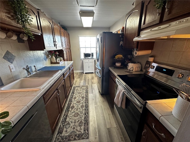 kitchen with decorative backsplash, appliances with stainless steel finishes, dark brown cabinets, and tile counters