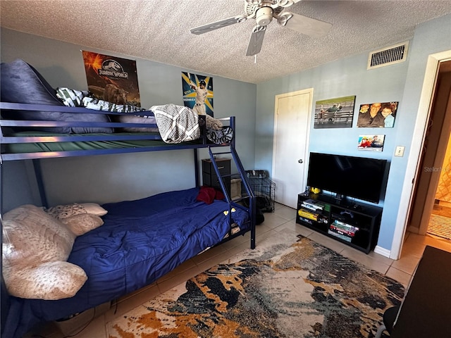 bedroom featuring ceiling fan, light tile patterned floors, and a textured ceiling