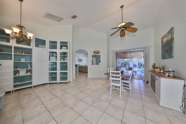 tiled dining space featuring lofted ceiling and ceiling fan with notable chandelier