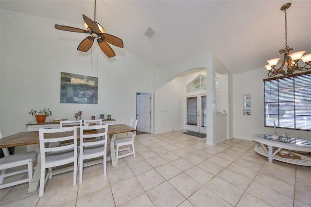 dining space with french doors, ceiling fan with notable chandelier, light tile patterned flooring, and vaulted ceiling