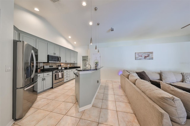 kitchen featuring pendant lighting, vaulted ceiling, decorative backsplash, light tile patterned floors, and appliances with stainless steel finishes