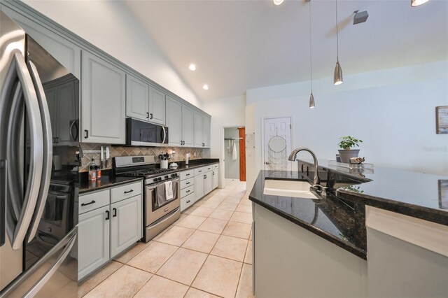 kitchen featuring gray cabinetry, sink, vaulted ceiling, decorative backsplash, and stainless steel appliances