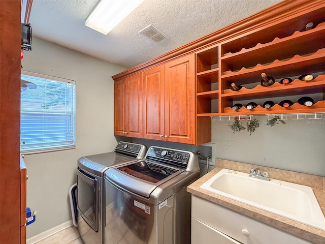 washroom featuring cabinets, a textured ceiling, sink, light tile patterned floors, and washing machine and clothes dryer