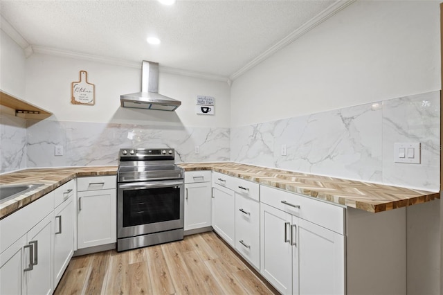 kitchen featuring butcher block countertops, white cabinetry, light wood-style floors, electric stove, and wall chimney range hood