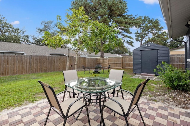 view of patio featuring outdoor dining space, a fenced backyard, an outdoor structure, and a shed