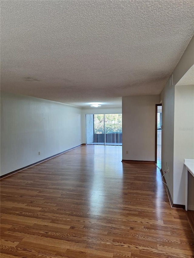 unfurnished room featuring dark wood-type flooring and a textured ceiling