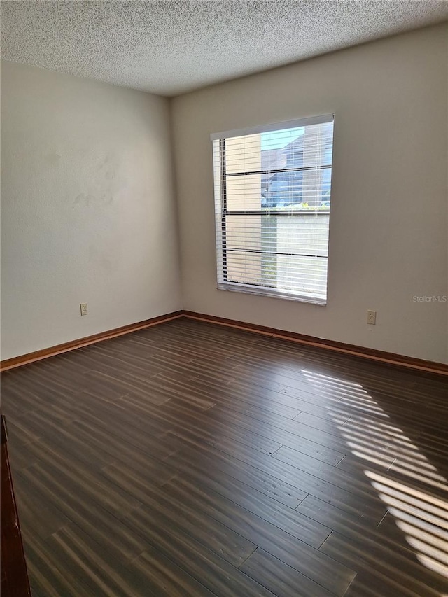 empty room with a textured ceiling and dark hardwood / wood-style floors