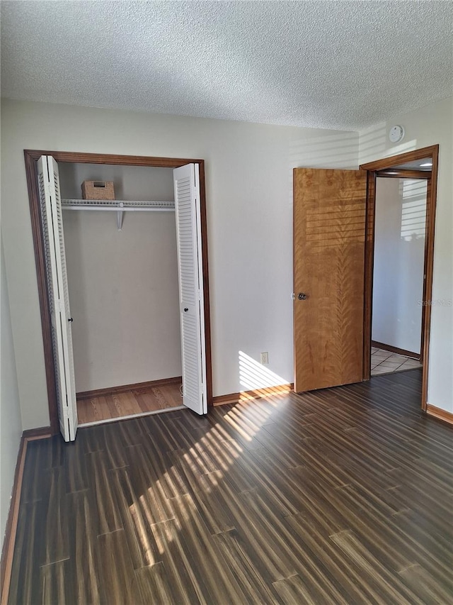 unfurnished bedroom featuring a closet, dark wood-type flooring, and a textured ceiling