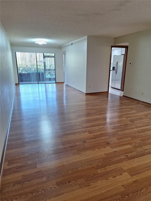 unfurnished room featuring a textured ceiling and dark hardwood / wood-style floors