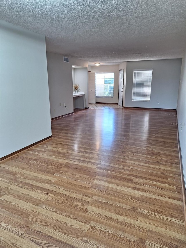 unfurnished room with light hardwood / wood-style flooring and a textured ceiling