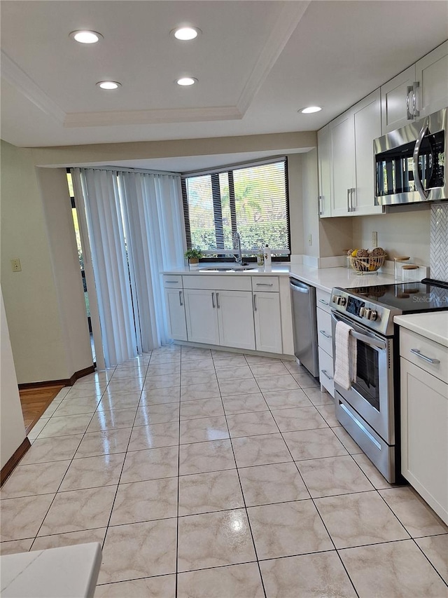 kitchen with a raised ceiling, white cabinets, and appliances with stainless steel finishes