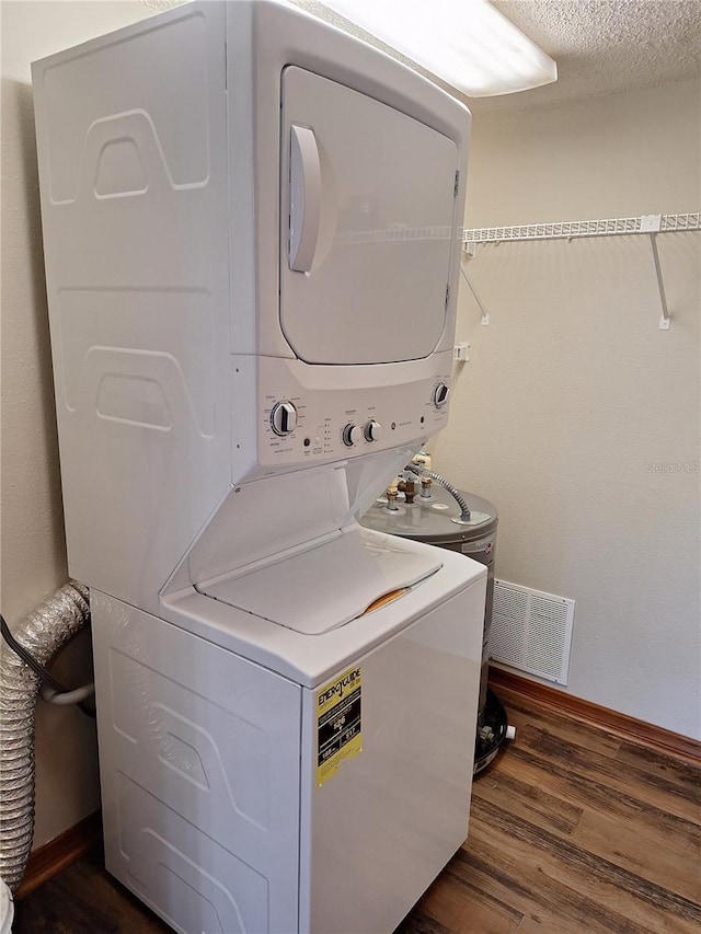 clothes washing area featuring a textured ceiling, dark wood-type flooring, and stacked washer and clothes dryer