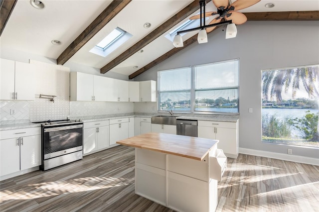 kitchen featuring stainless steel appliances, lofted ceiling with skylight, ceiling fan, dark wood-type flooring, and white cabinets