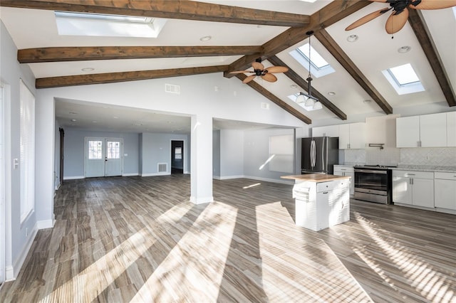 kitchen with appliances with stainless steel finishes, tasteful backsplash, a skylight, white cabinets, and a center island