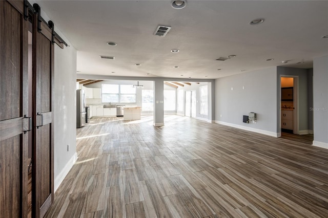 unfurnished living room featuring wood-type flooring and a barn door