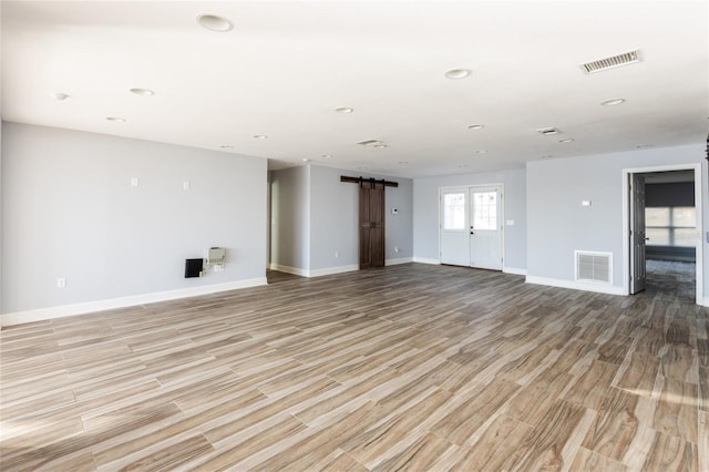 spare room with a barn door, light wood-type flooring, and french doors