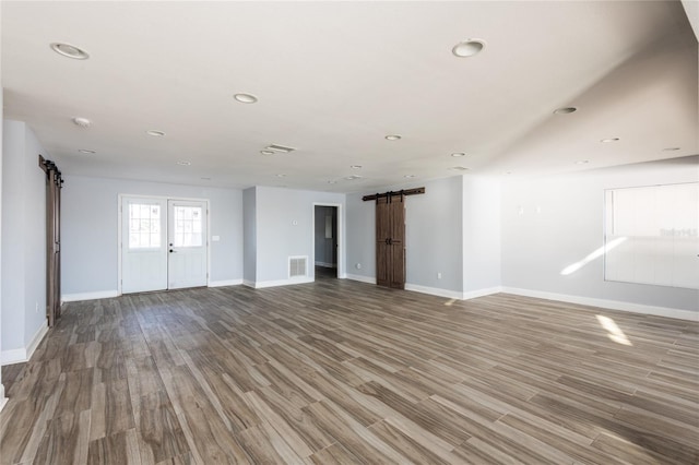 unfurnished living room with a barn door and hardwood / wood-style floors