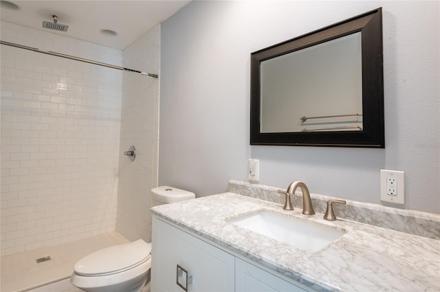 bathroom with toilet, vanity, and tiled shower