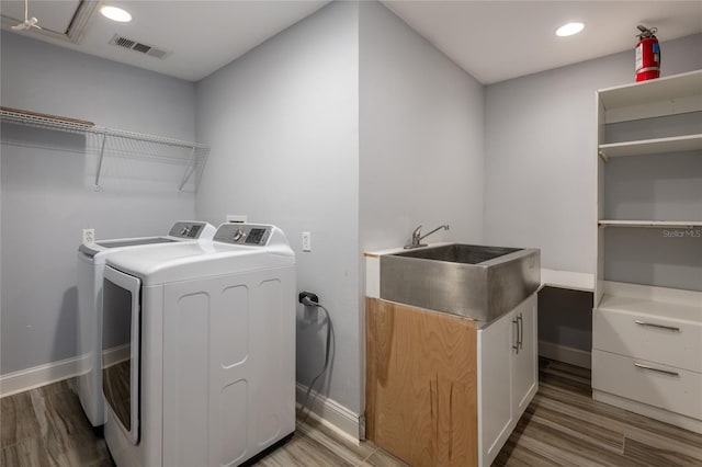 washroom with light wood-type flooring, washing machine and dryer, and sink