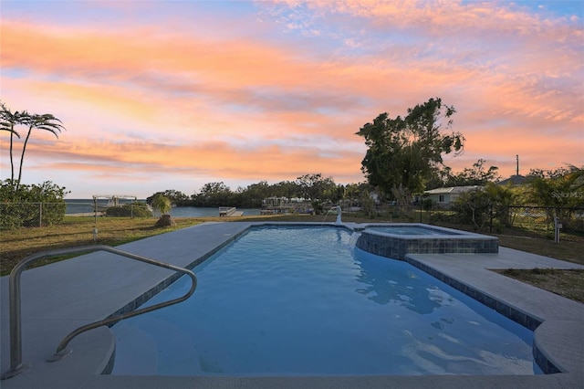 pool at dusk featuring an in ground hot tub