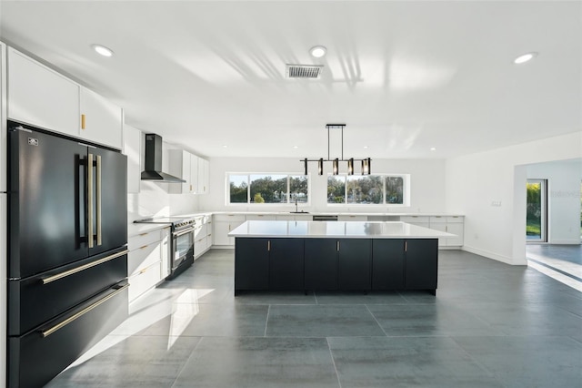 kitchen with a spacious island, white cabinetry, high end black fridge, electric stove, and wall chimney range hood