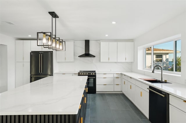 kitchen with decorative light fixtures, sink, white cabinets, black appliances, and wall chimney range hood