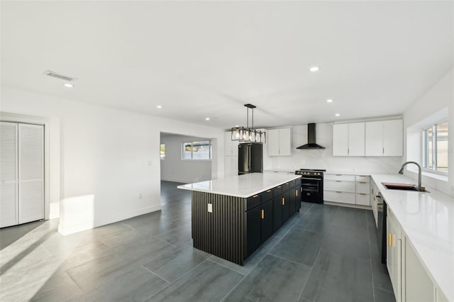 kitchen with sink, white cabinets, hanging light fixtures, a center island, and wall chimney range hood