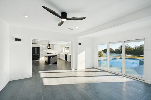 unfurnished living room featuring sink and ceiling fan