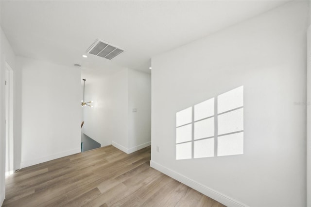 empty room featuring a notable chandelier and light hardwood / wood-style floors