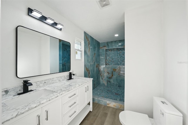 bathroom featuring vanity, a tile shower, and toilet