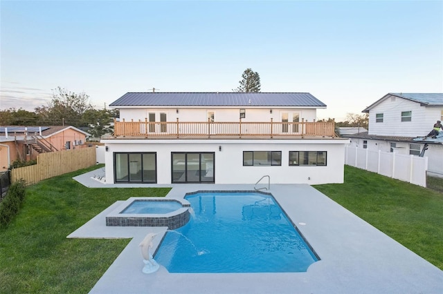 back of house with a patio, a balcony, a yard, and a pool with hot tub