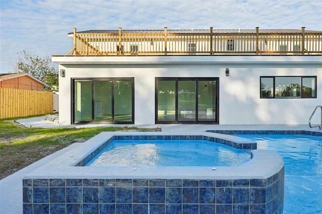 rear view of property with a swimming pool with hot tub and a balcony