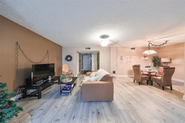 living room featuring light wood-type flooring and a textured ceiling