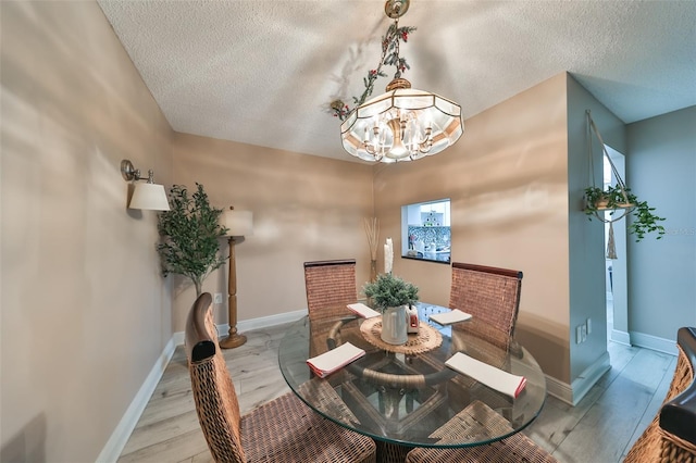 dining space featuring light hardwood / wood-style floors, a textured ceiling, and a chandelier