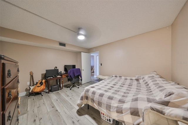 bedroom with ceiling fan, light hardwood / wood-style flooring, and a textured ceiling