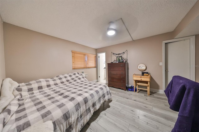 bedroom with a textured ceiling and light hardwood / wood-style flooring