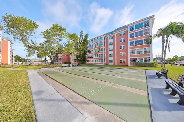 view of community with a yard and shuffleboard