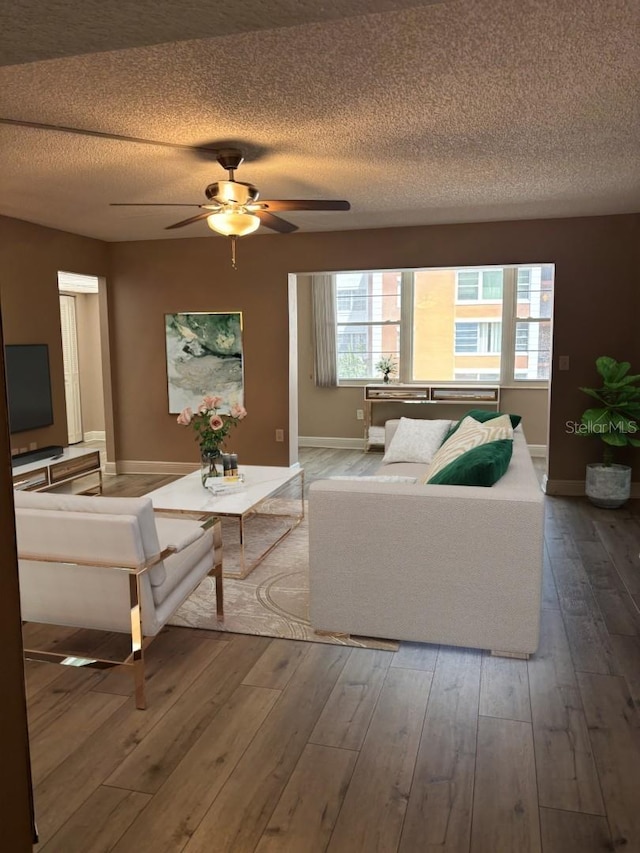 living room featuring hardwood / wood-style flooring, a textured ceiling, ceiling fan, and a healthy amount of sunlight