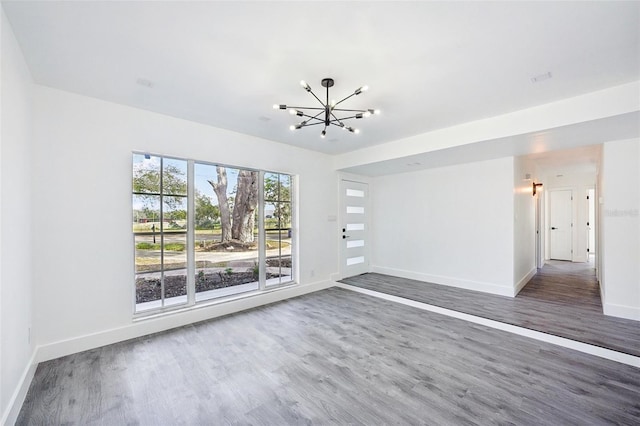 empty room with dark hardwood / wood-style floors and an inviting chandelier