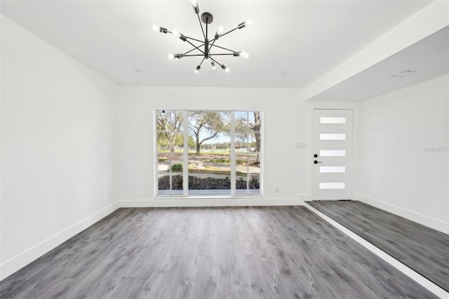 unfurnished living room with hardwood / wood-style floors and an inviting chandelier