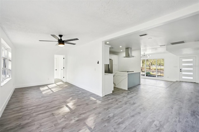 unfurnished living room with hardwood / wood-style floors, ceiling fan with notable chandelier, and beamed ceiling