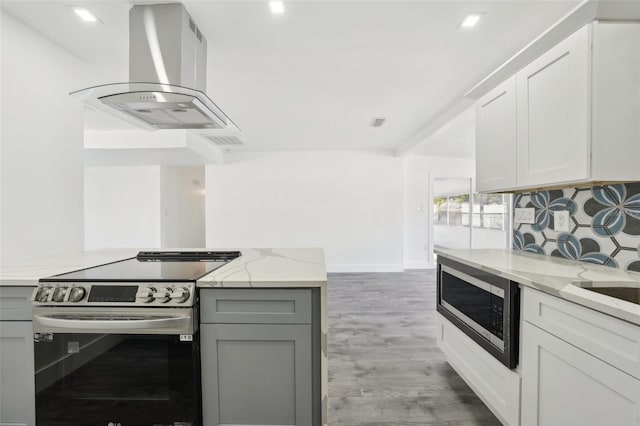 kitchen with appliances with stainless steel finishes, light stone counters, exhaust hood, gray cabinets, and white cabinetry