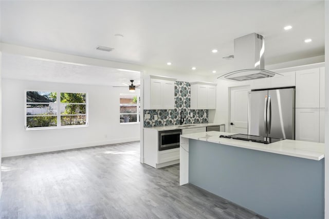 kitchen with appliances with stainless steel finishes, tasteful backsplash, island range hood, sink, and white cabinets