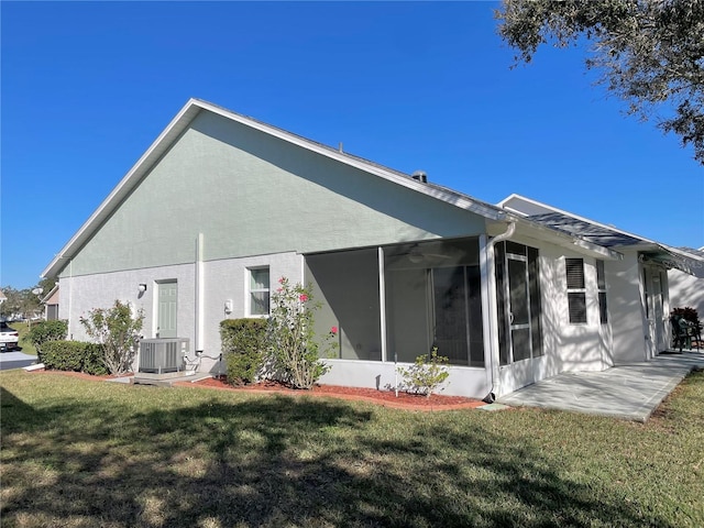 rear view of house with central air condition unit, a patio, a sunroom, and a lawn