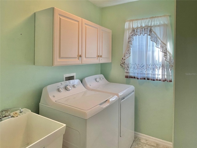 clothes washing area with sink, cabinets, and washer and dryer