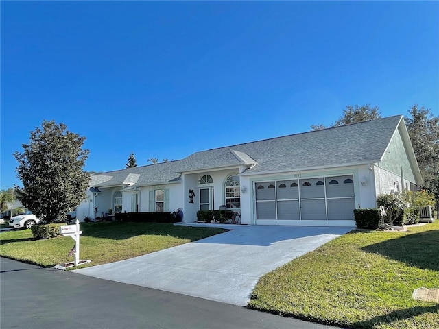 ranch-style house featuring a front lawn, concrete driveway, a garage, and stucco siding