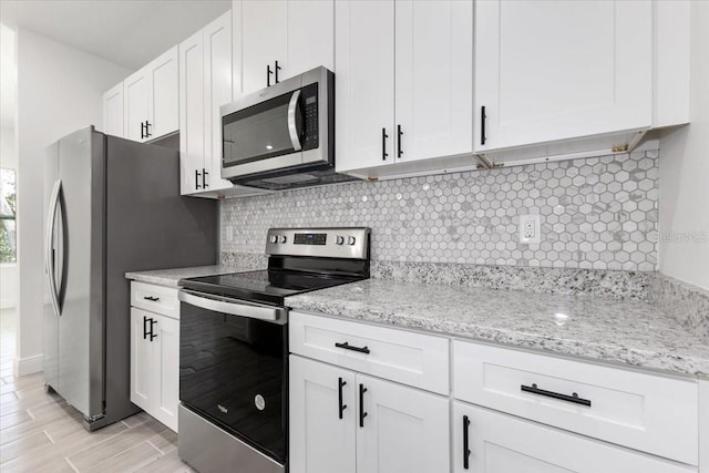 kitchen featuring white cabinets, stainless steel appliances, light stone counters, and tasteful backsplash